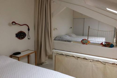 a white bedroom with a bed and a mirror at Appartement à 100 m du village de porquerolles in Porquerolles