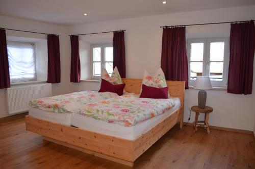 Schlafzimmer mit einem Holzbett mit roten Vorhängen in der Unterkunft Ferienwohnung Fenzl in Rimsting