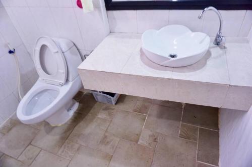 La salle de bains est pourvue de toilettes blanches et d'un lavabo. dans l'établissement พี่ดา เฮ้าส์ (P'Da House), à Hat Yai