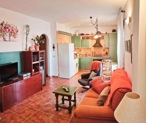 uma sala de estar com um sofá laranja e uma cozinha em Apartamentos Maria em Cómpeta