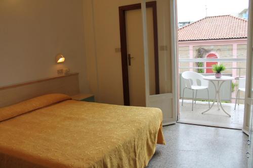 1 Schlafzimmer mit einem Bett und einem Balkon mit einem Tisch in der Unterkunft Hotel Madrid in Cattolica