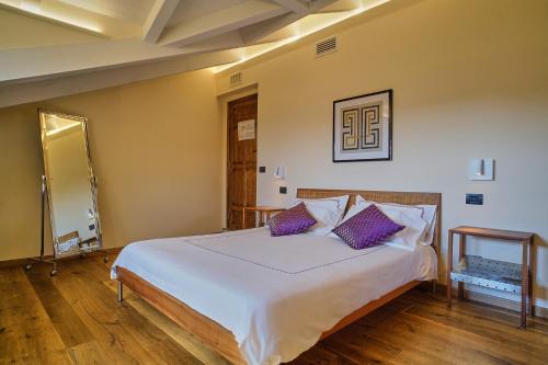a bedroom with a large white bed with purple pillows at Giarvino Boutique Guest House in Acqui Terme