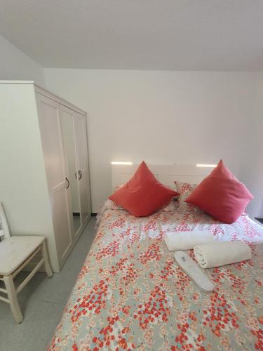 a bedroom with a bed with red pillows and a chair at Monolocale caterina in Corniglia