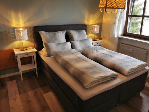 a bedroom with a bed with two pillows and two lamps at Ferienwohnung am See in Haidmühle