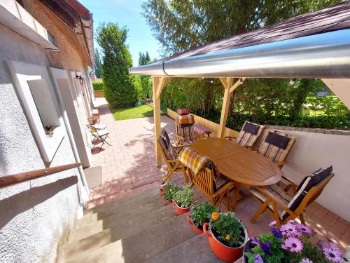 a patio with a wooden table and chairs and plants at Kilátás a tóra Apartman in Szigliget