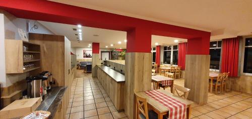 a restaurant with red walls and tables and chairs at Hotel Bigger Hof - Wirtshaus Platzhirsch am Jahnplatz in Olsberg
