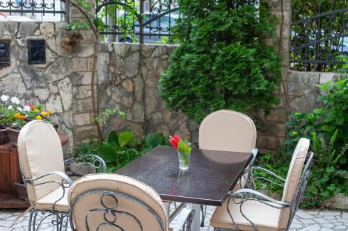 a table with chairs and a vase with a flower on it at Saki Apartments in Budva