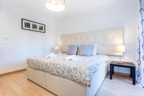 1 dormitorio blanco con 1 cama grande con almohadas azules en Seaview apartment - Estrela da Luz****, en Luz