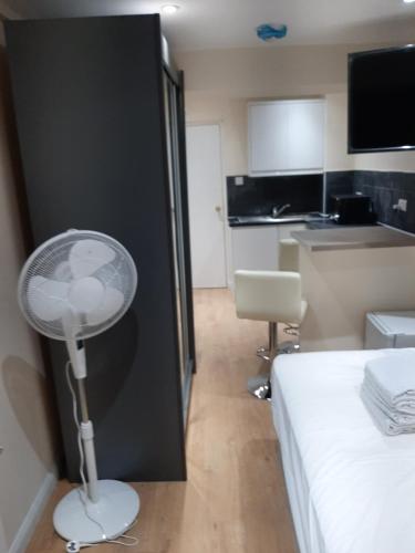 Cette chambre d'hôtel dispose d'un ventilateur à côté d'un lit. dans l'établissement Budget Ensuite Room in Thamesmead, à Londres