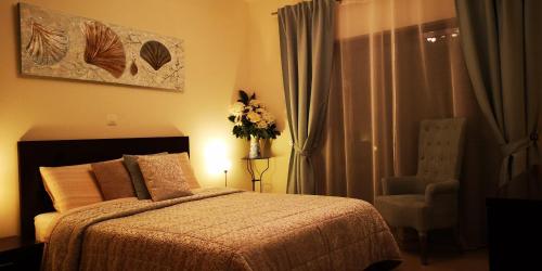 1 dormitorio con 1 cama, 1 silla y 1 jarrón de flores en Casa Marques, en Lagos
