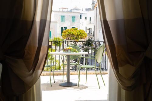 a table and chairs on a balcony looking out a window at Palazzo Indelli in Monopoli