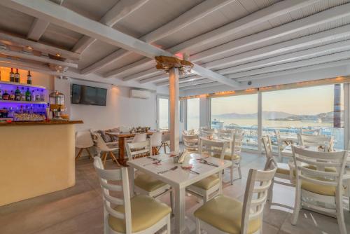 een eetkamer met een tafel, stoelen en ramen bij Ibiscus Boutique in Mykonos-stad
