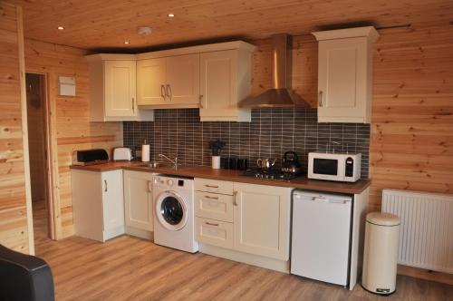 a kitchen with white cabinets and a washer and dryer at FOYLE VIEW CABIN in Greencastle