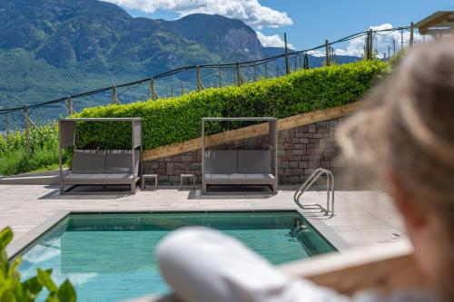 a woman is standing next to a swimming pool at Vineus Tramin in Termeno