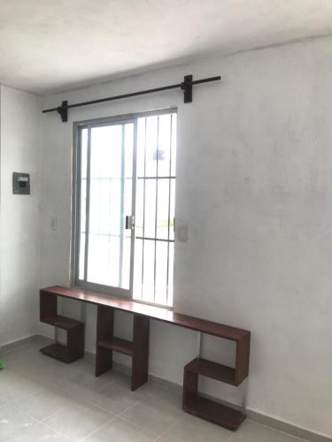 un banco de madera en una habitación con ventana en Departamento sencillo en CAMPECHE EX HACIENDA KALA en Campeche