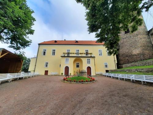 a large yellow building with flowers in front of it at Penzion hradu Svojanov in Svojanov