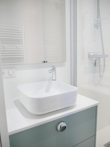 une salle de bain blanche avec un lavabo et une douche dans l'établissement Appartement Front de Mer à Carnac Plage, à Carnac