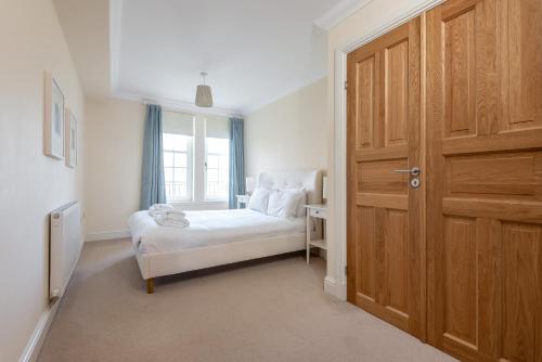 a bedroom with a bed and a wooden door at Adamson Court - 2 Bedroom Flat - Free Parking in St. Andrews