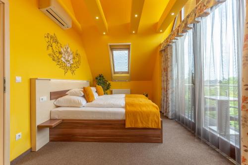 a bedroom with yellow walls and a bed with yellow sheets at Hotel Mayer Alsóörs in Alsóörs