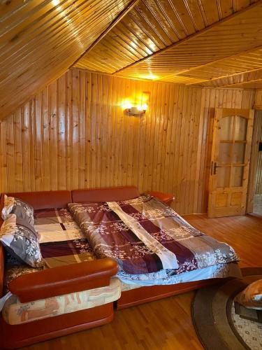 a bed in a room with wooden walls at Casa Alesi in Dragoslavele
