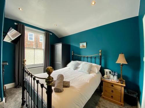 a bedroom with blue walls and a bed and a window at Blenheim Guest House in York