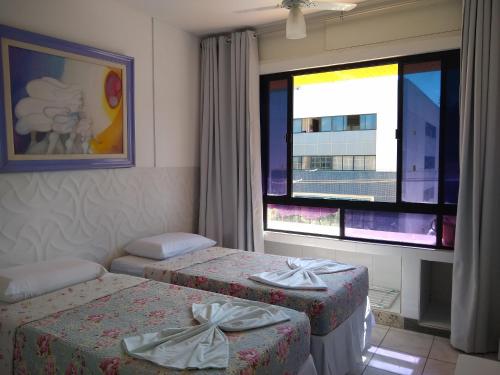 a hotel room with two beds and a window at Flat na Praia do Farol da Barra in Salvador