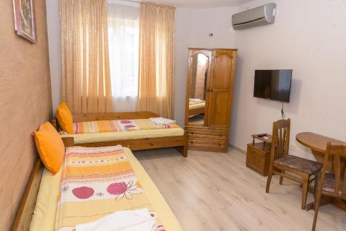 a small room with two beds and a television at Къща за гости Мони in Sandanski