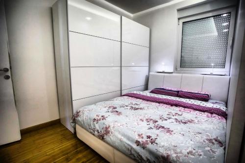 a bedroom with a bed with a white headboard and a window at APARTMAN SIMIC - STAN NA DAN in Bogatić