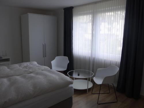 a bedroom with a bed and two chairs and a glass table at Pension Schneider in Cochem
