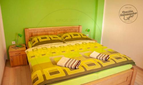 a bedroom with a large yellow bed with two pillows at Penzion Salamander in Terchová