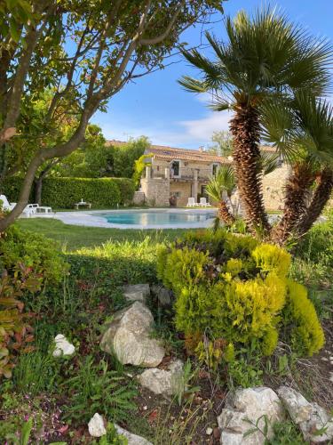 a swimming pool with a palm tree and a house at Logis Le Mas de Valaurie in Valaurie