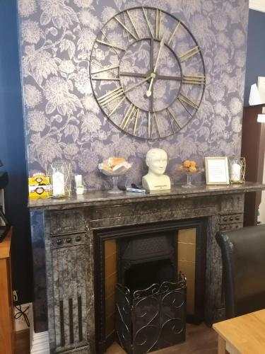 a fireplace with a large clock on a wall at The Epperstone in Llandudno