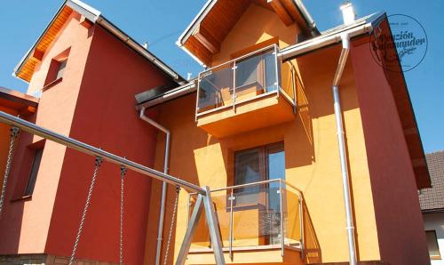 a red and yellow building with a balcony at Penzion Salamander in Terchová
