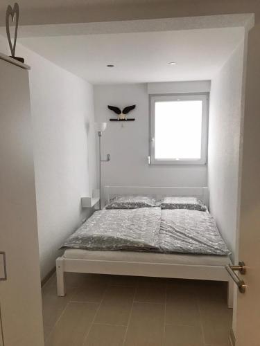 a bed in a white room with a window at Ferienwohnung kleines Zuhause in Mülheim an der Ruhr