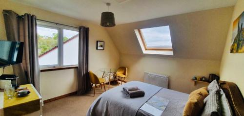 a bedroom with a bed and two windows and a table at Feochan Rooms Portree in Portree