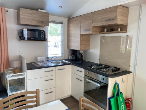 a small kitchen with a stove and a sink at Mobil Home 3 chambres climatisé tout équipé in Valras-Plage