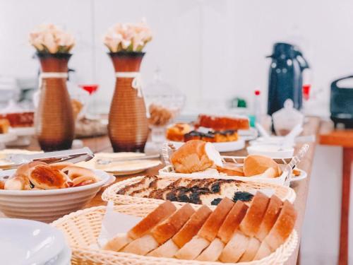 a table topped with baskets of bread and pastries at Nacional Park Hotel Lages in Lages