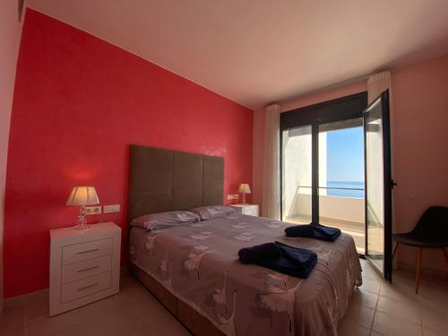 - une chambre dotée d'un mur rouge avec un lit et une fenêtre dans l'établissement Casa Playa Vista, à Mojácar