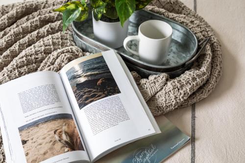 “Hygge” 3BDR townhouse, Close to beach, park & wineries! في ترافيرس سيتي: كتاب مفتوح على طاولة بجانبه نبتة وسلة