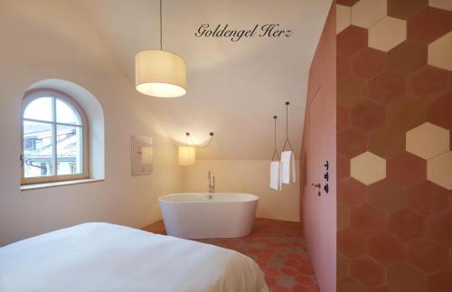 sypialnia z łóżkiem i wanną w pokoju w obiekcie Goldengel Design - Suiten im historischen Ortskern von Kaltern w mieście Caldaro