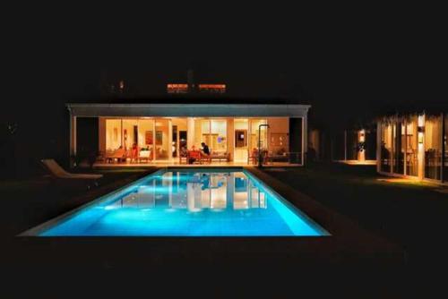 a large swimming pool in front of a house at night at Vikara in Olón