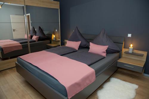 um quarto com uma cama com almofadas cor-de-rosa e um espelho em Schöner Wohnen em Friesenheim