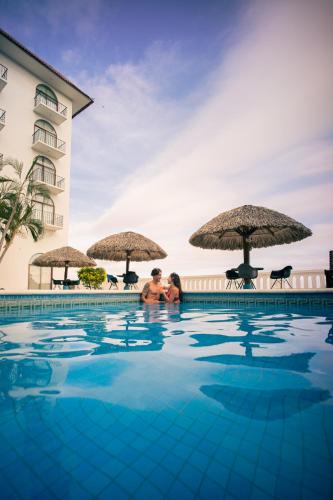 a man and woman standing in the swimming pool at a hotel at Hotel Caracol Plaza in Puerto Escondido