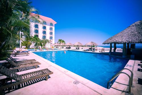 a swimming pool with lounge chairs and a hotel at Hotel Caracol Plaza in Puerto Escondido