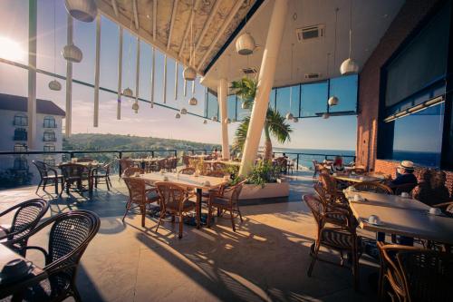 a restaurant with tables and chairs and a view of the ocean at Hotel Caracol Plaza in Puerto Escondido