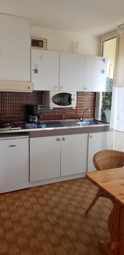 une cuisine avec des armoires blanches et une table en bois dans l'établissement Studio Naturiste 