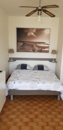 une chambre avec un lit blanc avec un ventilateur de plafond dans l'établissement Studio Naturiste 