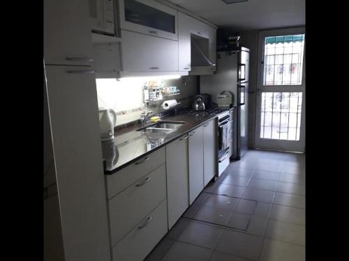 cocina con armarios blancos y ventana grande en Casa cerca del centro Bed&breakfast en Mendoza