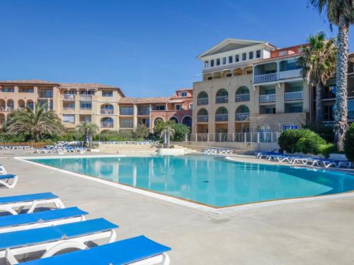 une grande piscine avec des chaises longues et un bâtiment dans l'établissement Appartement T2 avec piscine a 100 m de la plage, à Six-Fours-les-Plages