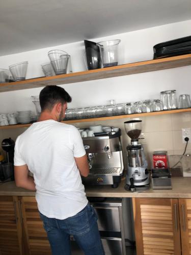 a man standing in front of a coffee maker in a kitchen at Ibiscus Boutique in Mýkonos City